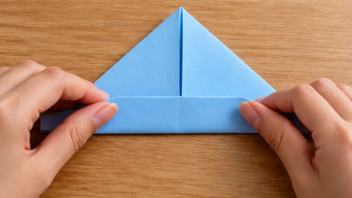 Manos levantando la solapa inferior del pliegue triangular de un barco de papel