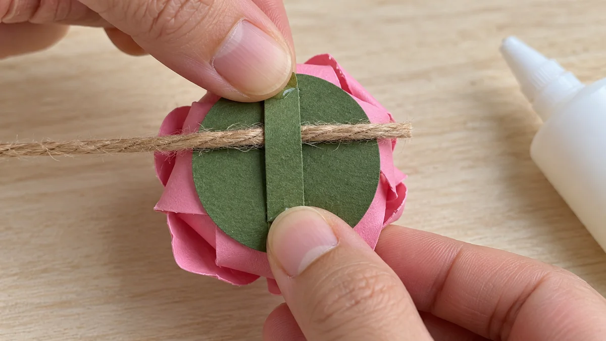 Cordón sujeto por una tira de refuerzo sobre el disco trasero de una rosa de papel
