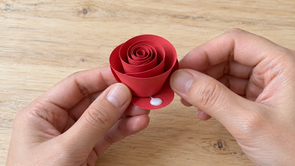 Base redonda con pegamento bajo una rosa de papel enrollada